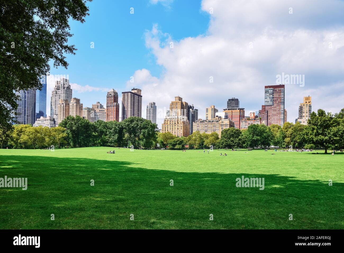 Menschen entspannen und genießen von einem sonnigen Tag im Central Park. New York City Skyline im Hintergrund. Freizeit Freizeit und Reisen Konzept. New York City. Unite Stockfoto