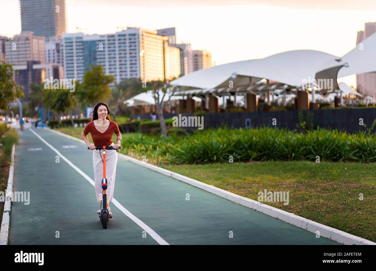 Frau reiten Elektroroller für den Transport in einer modernen Stadt Umgebung Stockfoto