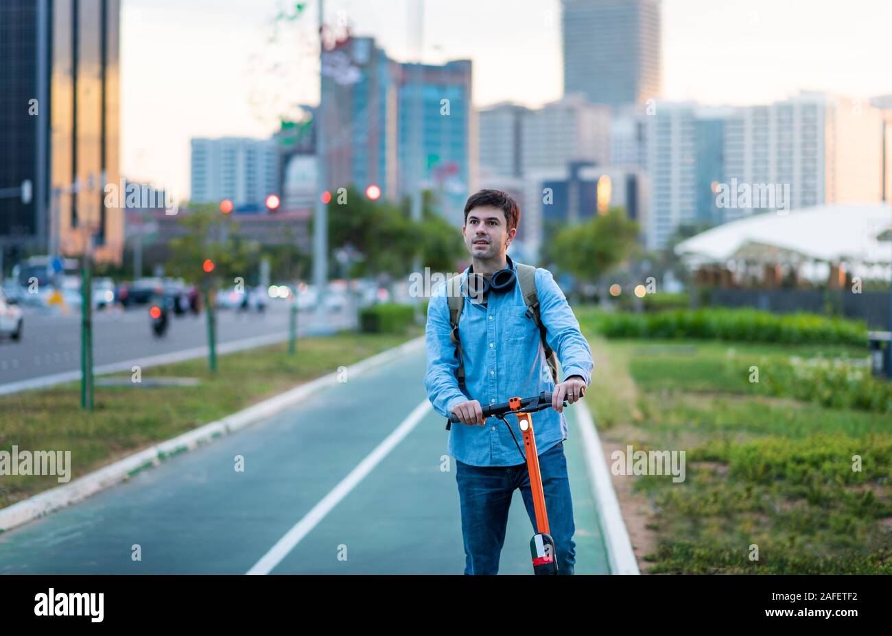 Mann mit elektrischer Roller für den Transport in einer modernen Stadt Umgebung Stockfoto