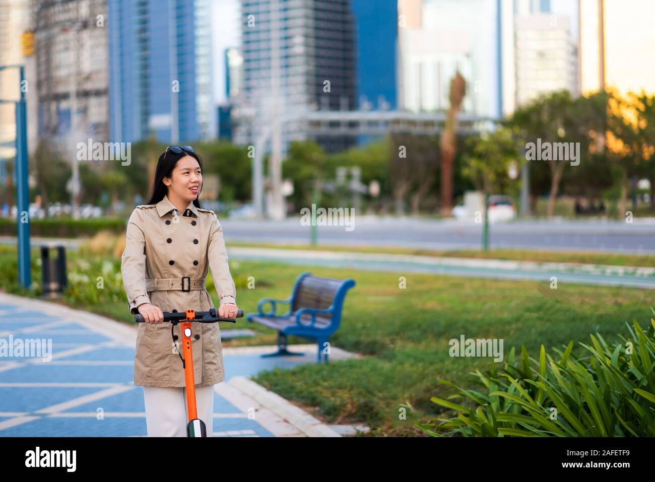 Frau mit Elektroroller für den Transport in einer modernen Stadt Umgebung Stockfoto