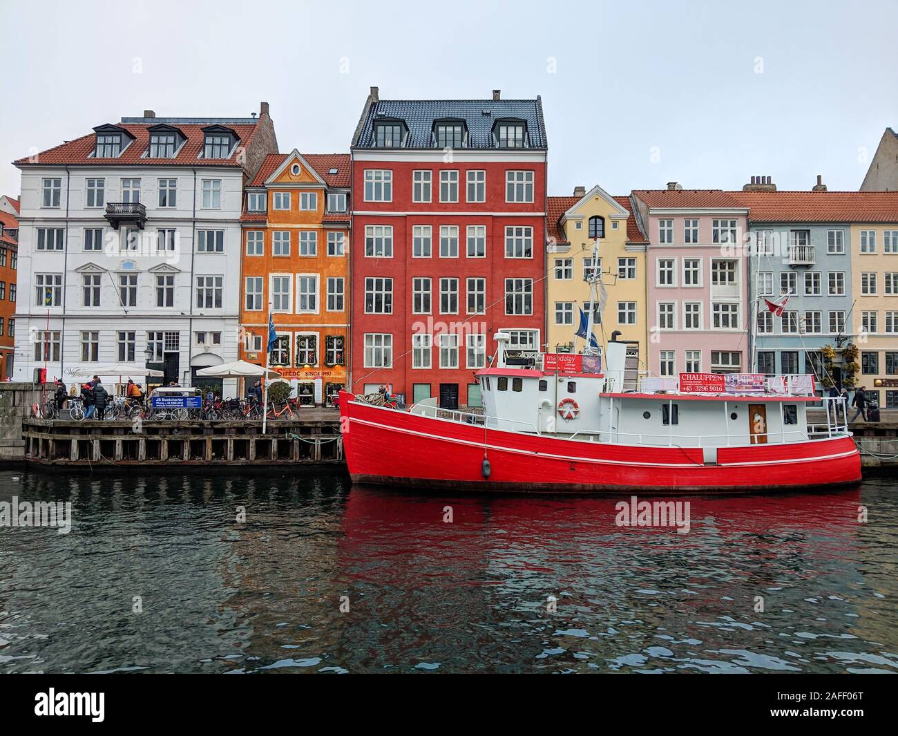 Farbenfrohe Gebäude und einem roten Boot im Wasser an einem bewölkten Tag in Nyhavn in Dänemark Stockfoto