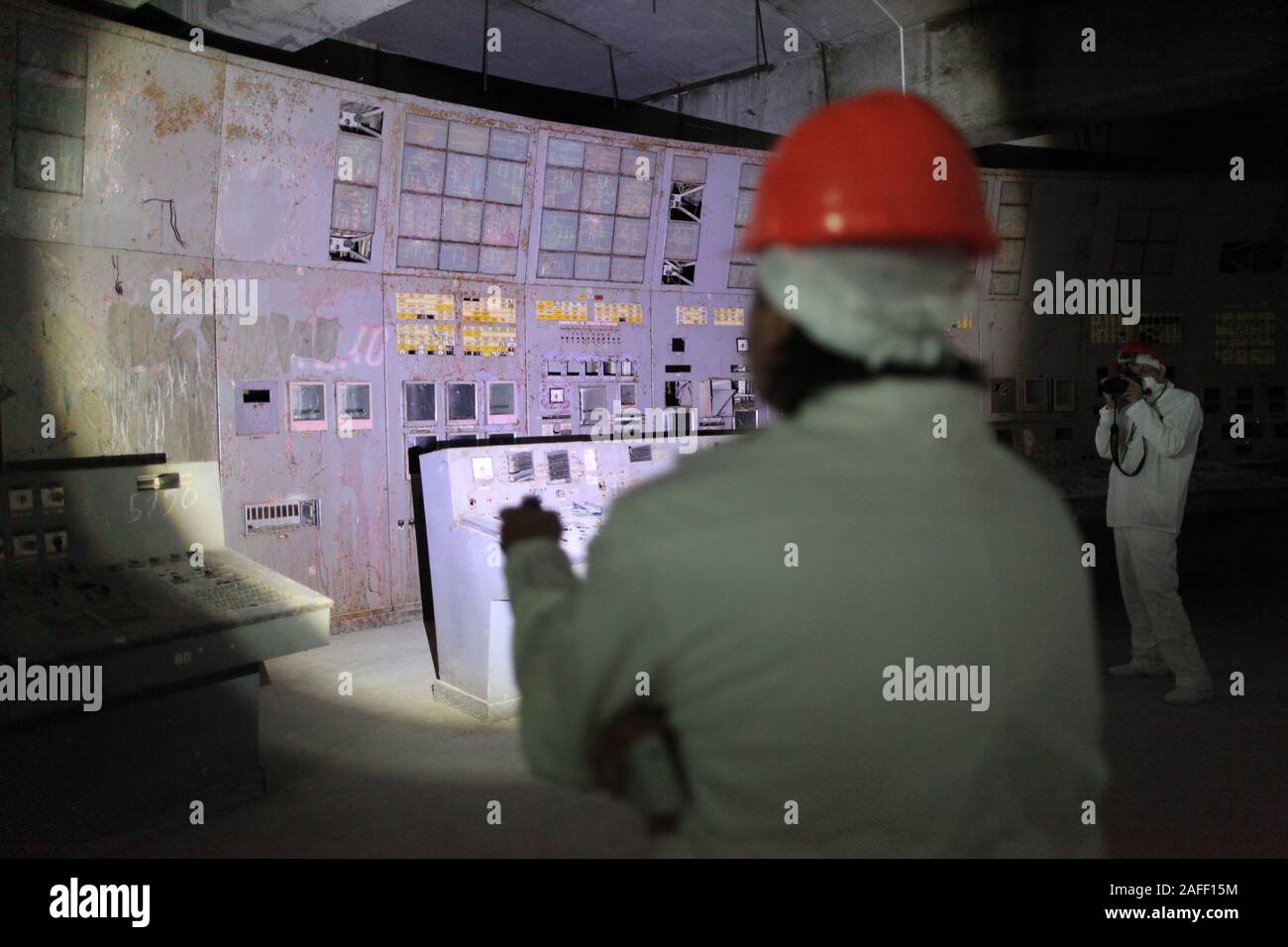 Touristen, die in den Kontrollraum des Reaktors vier von Tschernobyl, der Standort der weltweit Verheerendsten nuklearen Katastrophe. Die Zimmer des ehemaligen Kernkraftwerk ist, wo Ingenieure den Reaktor der Kühlpumpen als Teil eines Safety Test im April 1986, die zu einer Explosion, die mindestens 28 Menschen in der unmittelbaren Nachkriegszeit getötet und die Umgebung verschmutzt Led abgeschaltet. Die Zimmer, unter einem 36.000-Tonnen Stahl Auffangwannen Bogen gelegen, hat seinen ursprünglichen Displays und Panels der Schaltflächen. Tschernobyl, Ivankiv Rajon, Oblast Kiew, Ukraine, Europa Stockfoto