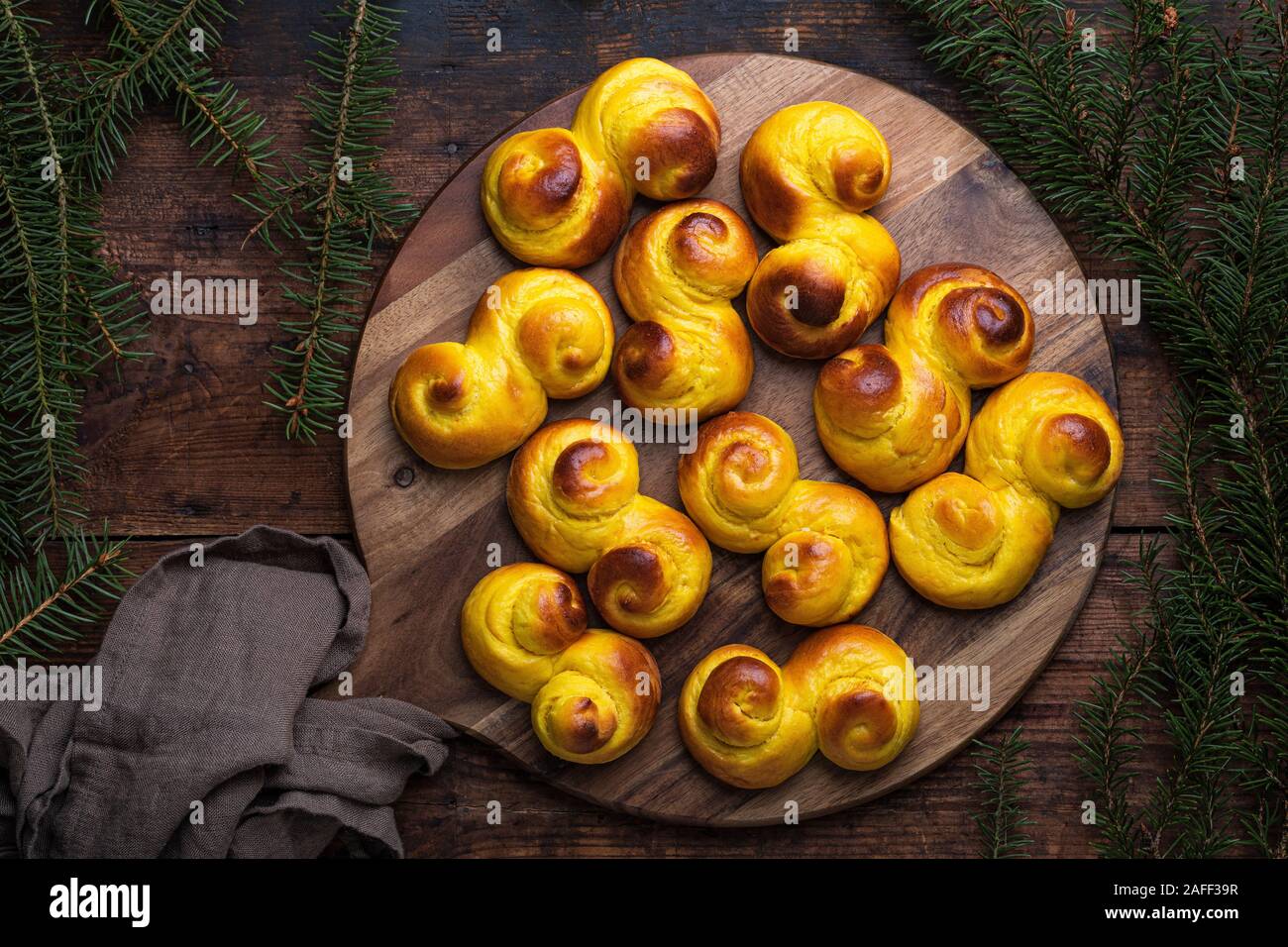 Frisch gebackene hausgemachte Schwedische traditionellen s-förmige Safran Brötchen, auch als lussebullar oder saffransbröd bekannt. Von oben flach auf dunklem Holz gesehen Stockfoto