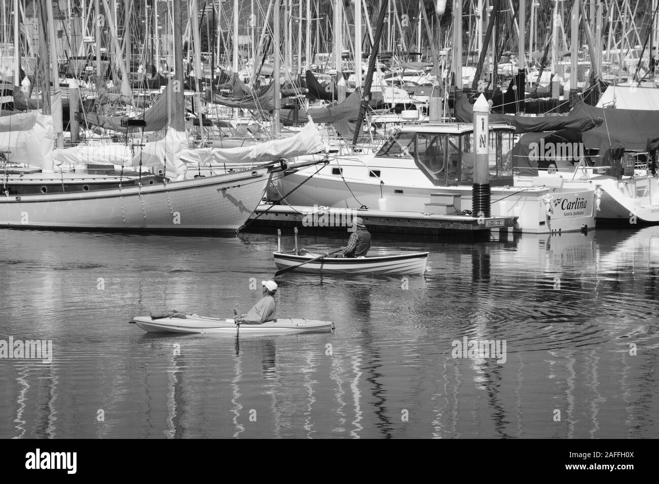 Ein Paddler und eine kanutin, Reisen in entgegengesetzte Richtungen an der Marina in den Hafen von Santa Barbara, Santa Barbara, CA, in Schwarz und Weiß Stockfoto