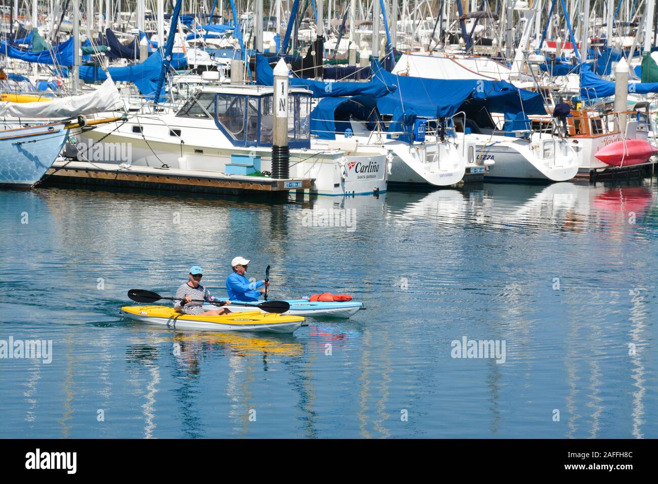 Ein Sitz, Paar mittleren Alters Manöver ihre Kajaks um den angedockten Segelboote und Yachten in der Marina am Hafen von Santa Barbara, Santa Barbara, CA Stockfoto