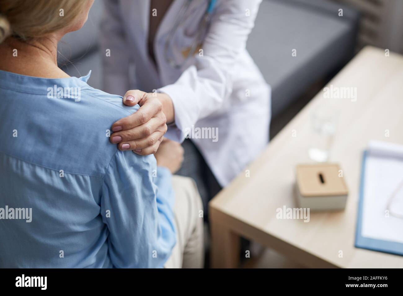 Hohen winkel Nahaufnahme des unkenntlich Ärztin über die Hand auf die Schulter der reifen Frau, während ihr tröstend bei der Beratung in der medizinischen Klinik, Stockfoto