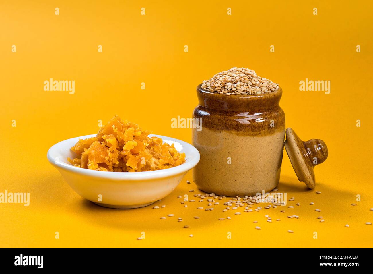 Sesamsamen in Tontopf mit Jagrezucker in Schüssel auf gelbem Hintergrund Stockfoto