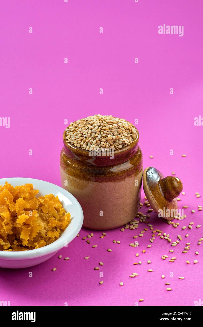 Sesamsamen in Tontopf mit Jagrezucker in Schüssel auf rosa Hintergrund Stockfoto
