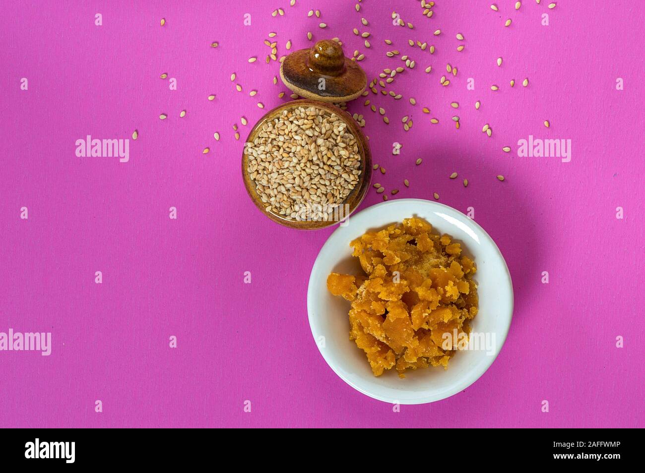 Sesamsamen in Tontopf mit Jagrezucker in Schüssel auf rosa Hintergrund Stockfoto
