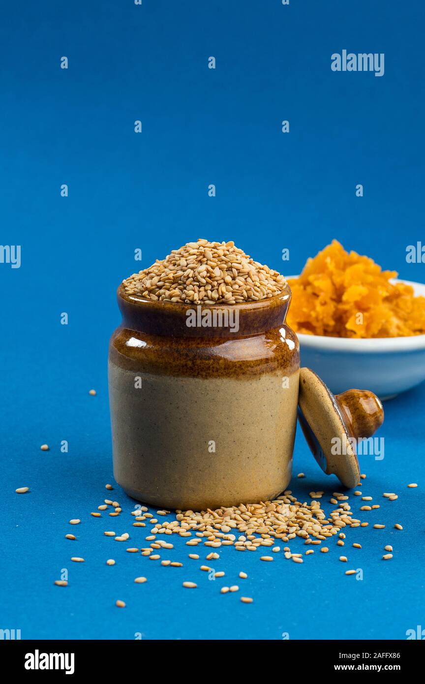Sesamsamen in Tontopf mit Jagrezucker in Schüssel auf blauem Hintergrund Stockfoto