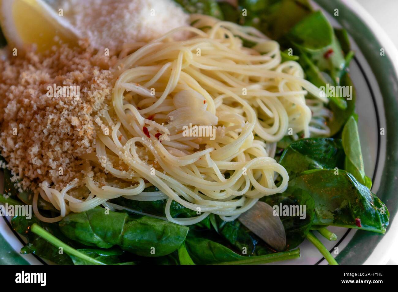 Close-up auf capellini Angel hair Pasta mit nativem Olivenöl, Spinat, frischer Zitrone, Chili Flocken, Knoblauch und gerösteten Brotkrumen, Abendessen Betrachtungswinkel Stockfoto