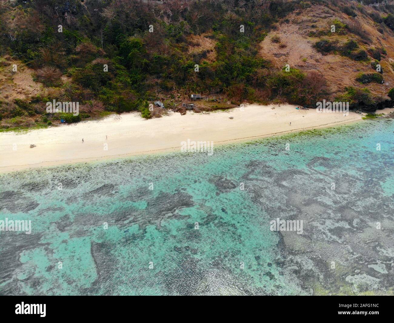 Luftaufnahme von einer erstaunlichen kleiner Strand mit Felswand in Bali. Schöne Meer Wasser mit Wellen zum Surfen. Ozean Landschaft, Urlaub Stockfoto