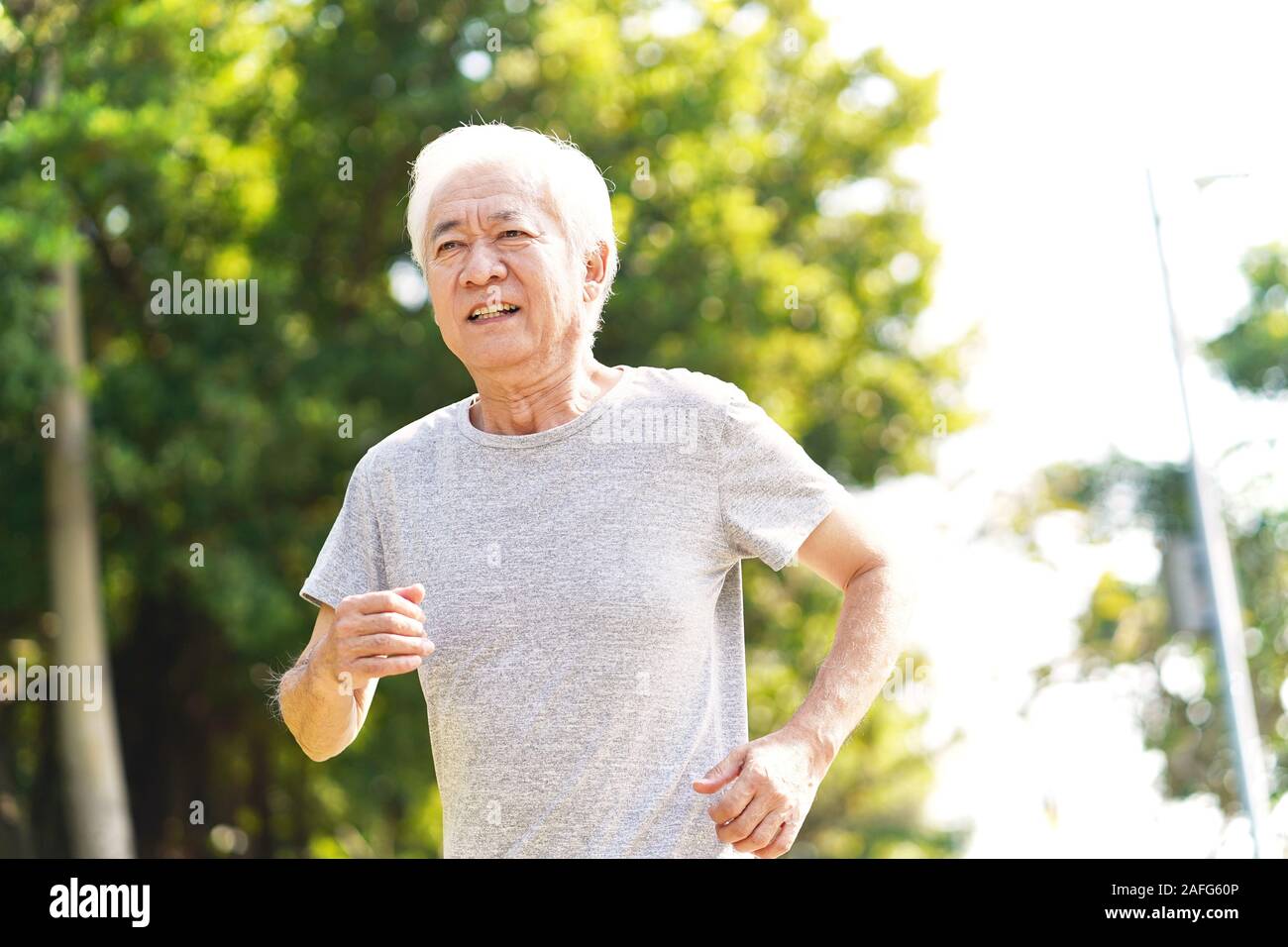 Senior asiatischer Mann joggen Laufen draußen im Park Stockfoto