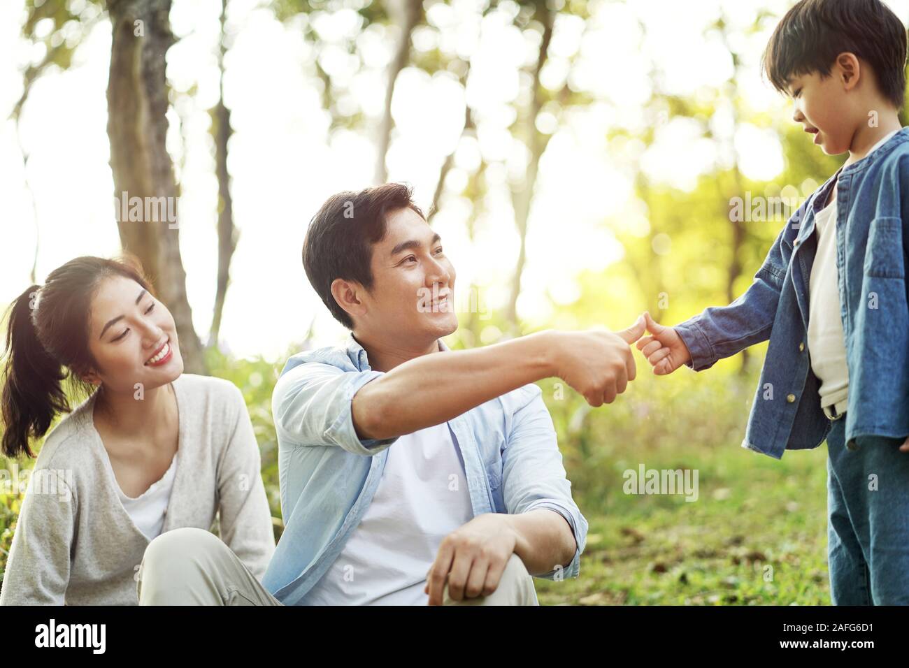 Asiatische Vater und Sohn Versiegelung ist ein Abkommen, das durch Drücken der Daumen zusammen draußen im Park Stockfoto