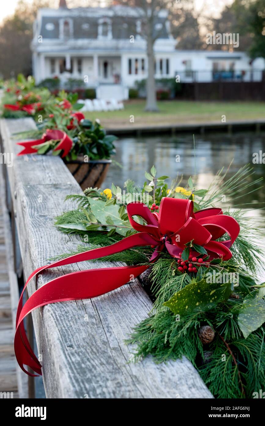 Holzbrücke in St. Michaels, MD, dekoriert mit immergrünen und roten Bögen während der Weihnachtszeit. Stockfoto