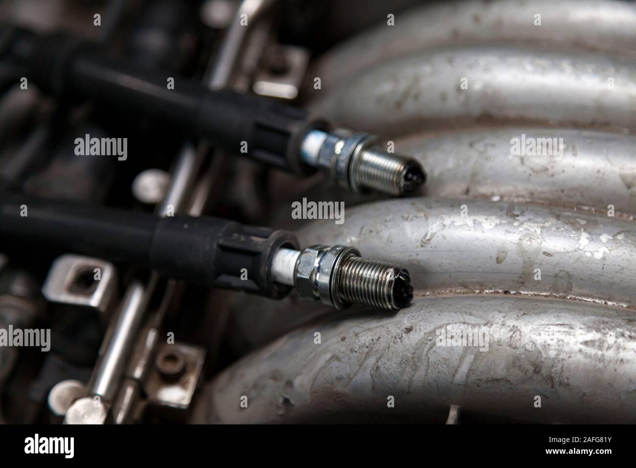 Zündkerzen mit Hochspannung Kabel am Motor unter der Motorhaube eines Autos  während der Diagnose und Reparatur in einer Werkstatt für Fahrzeuge. Auto  service Industr Stockfotografie - Alamy