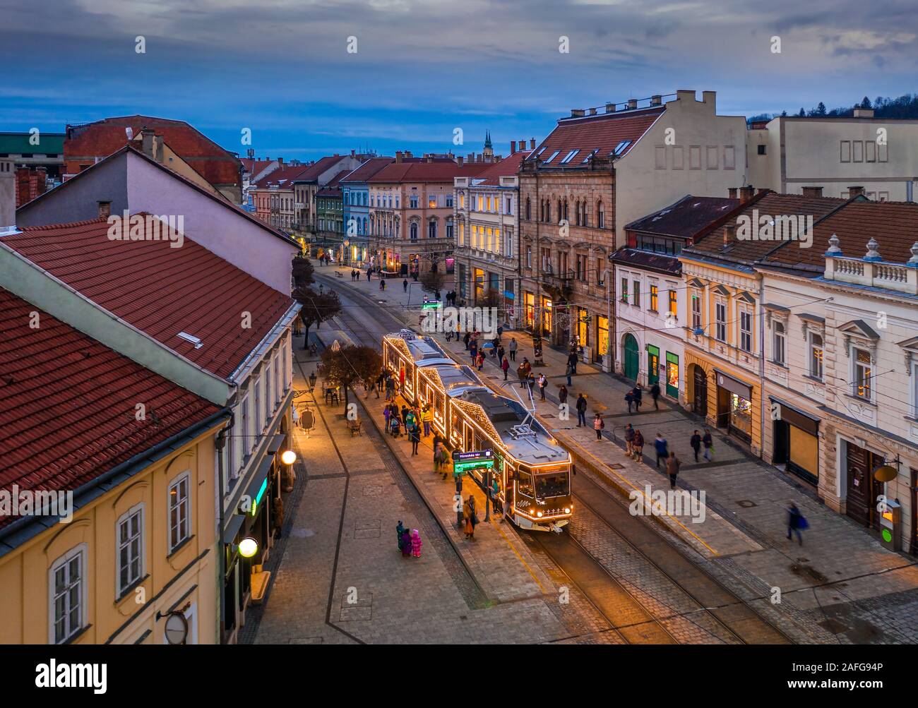 Miskolc, Ungarn - weihnachtlich geschmückten Licht Straßenbahn- und traditionelle Häuser an der Hauptstraße von Miskolc, Borsod-Abauj-Zemplen County in der Dämmerung Stockfoto