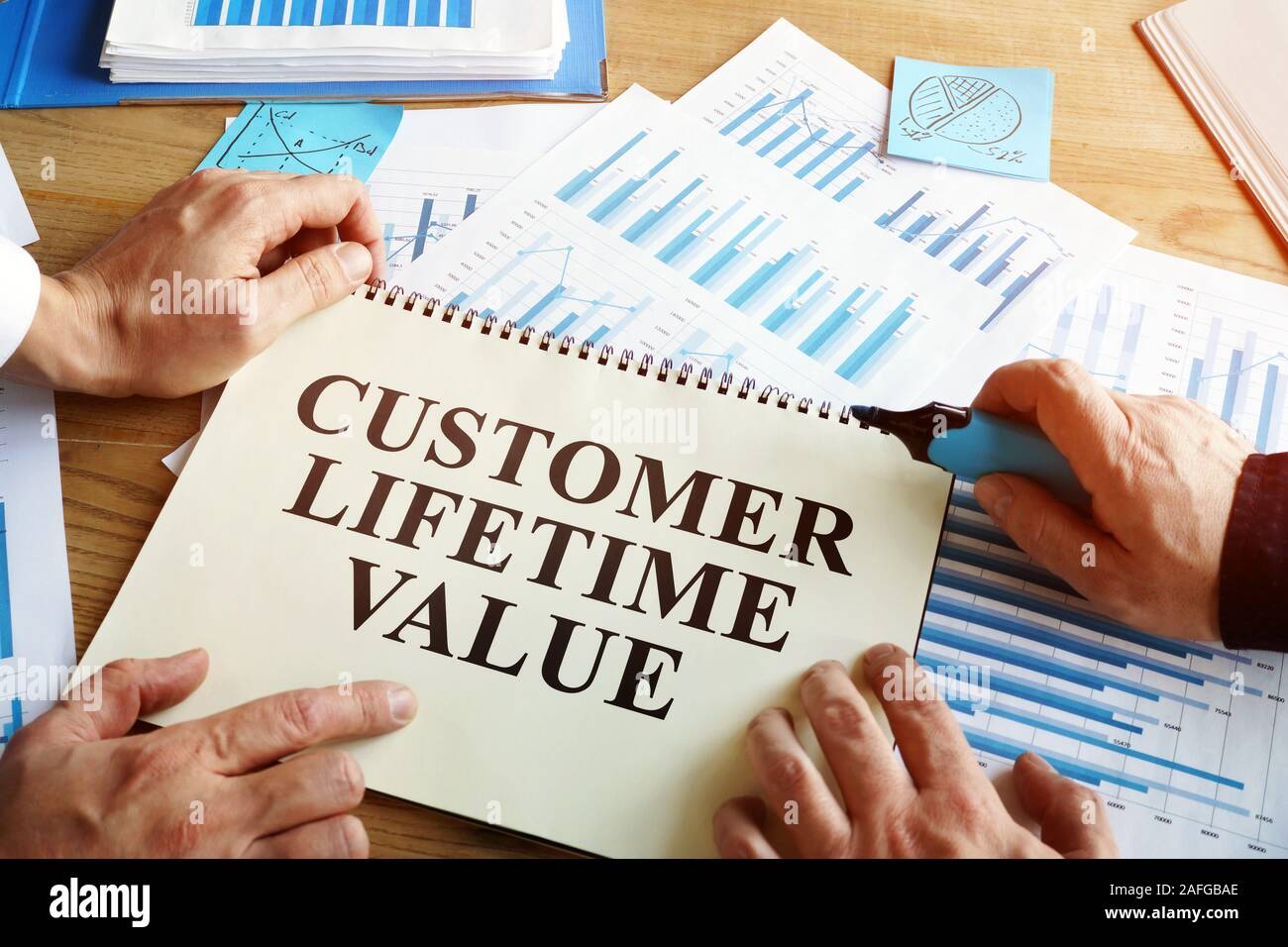 Männer lesen Customer Lifetime Value Konzeption in Buch. Stockfoto