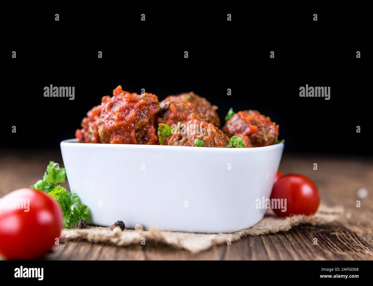 Hackfleischbällchen mit Tomatensauce (und frischen Kräutern) auf Holz- Hintergrund (selektive Fokus) Stockfoto