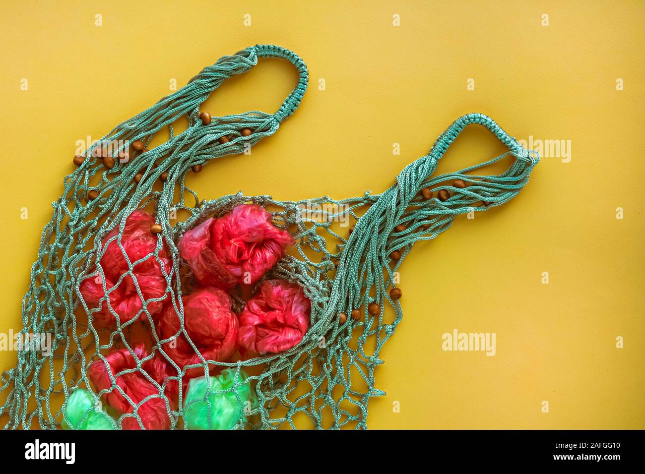 Net Tasche voll von künstlichen Früchten von grünen und roten Plastiktüten. Keine Kunststoff-Konzept. Umweltprobleme. Stockfoto