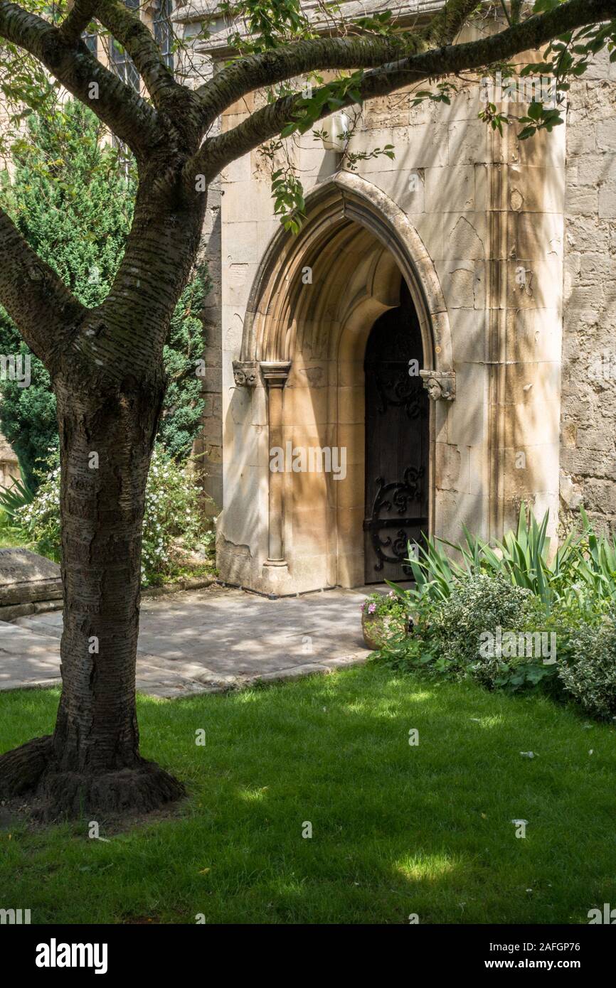 Hübsche, sonnenbeleuchtete, gotische Bogenkirche Eingangstür im Schatten des Kirschbaums im Sommer, St. Georges Kirche, Stamford, Lincolnshire, England, UK Stockfoto