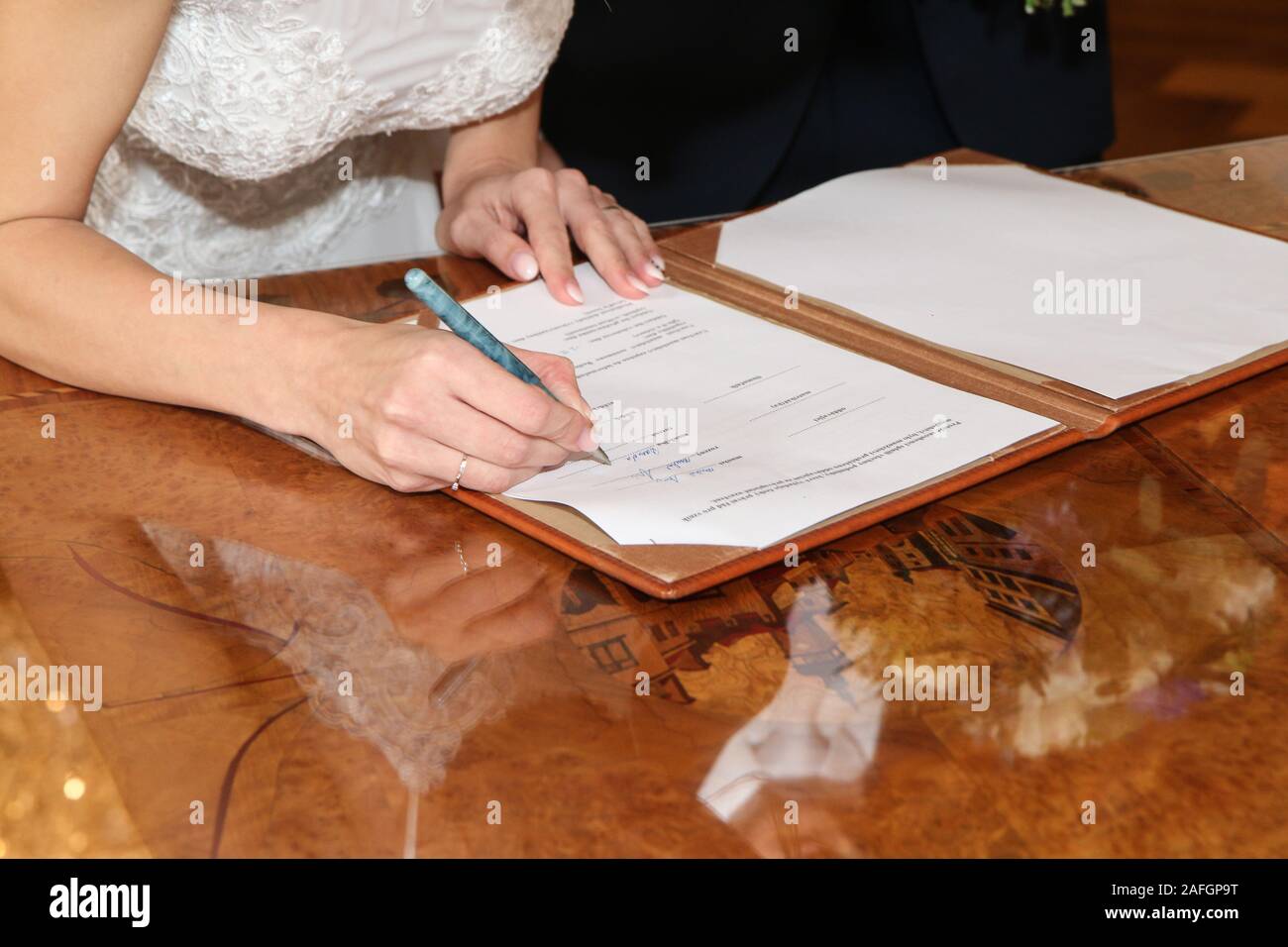 Das Detail aus einer Hochzeitszeremonie. Die Braut ist signaturing das Dokument nach der Zeremonie mit ihrem neuen Namen. Stockfoto