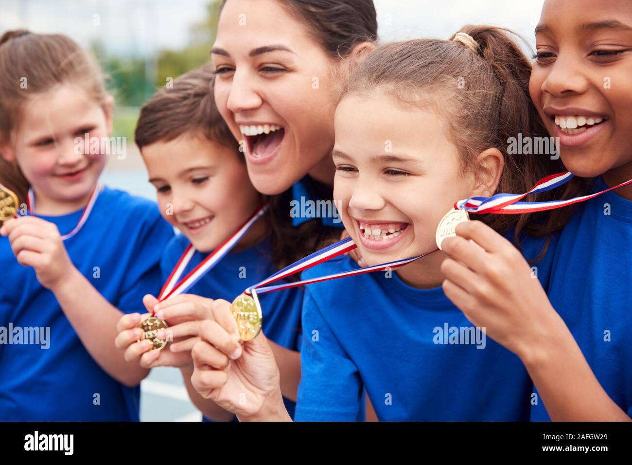 Kinder mit weiblichen Trainer zeigen, ein Sieger Medaillen auf Sport Tag Stockfoto