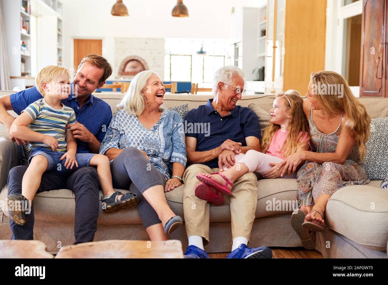 Multi-Generation Familie sitzt auf dem Sofa zu Hause Entspannen und Plaudern Stockfoto