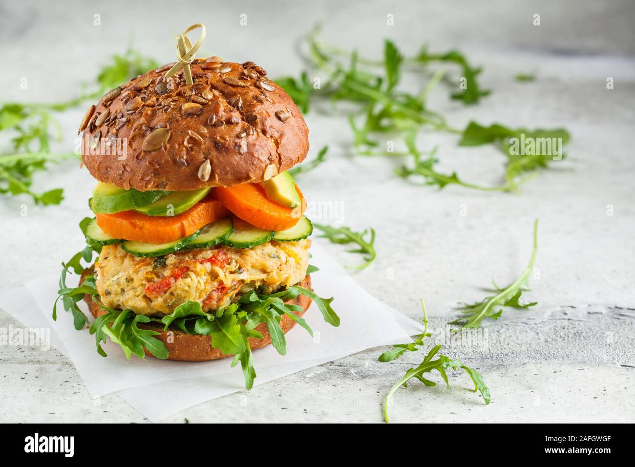 Vegane Burger mit pflanzlichen Schnitzel, Süßkartoffel, Avocado, Gurke und Rucola. Gesunde vegane Ernährung Konzept. Stockfoto