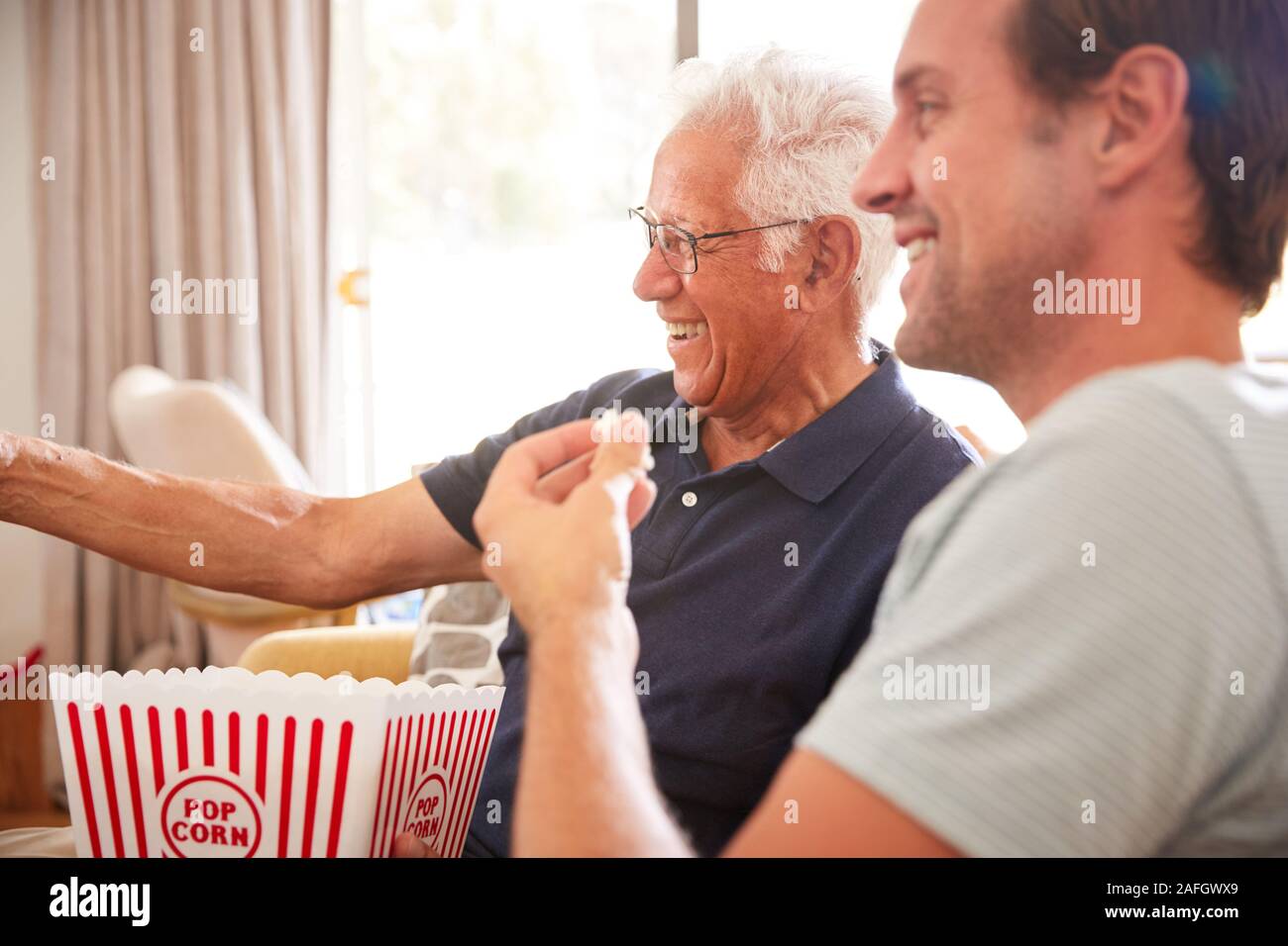 Vater mit erwachsenen Sohn Essen Popcorn anschauen Film auf dem Sofa zu Hause zusammen Stockfoto