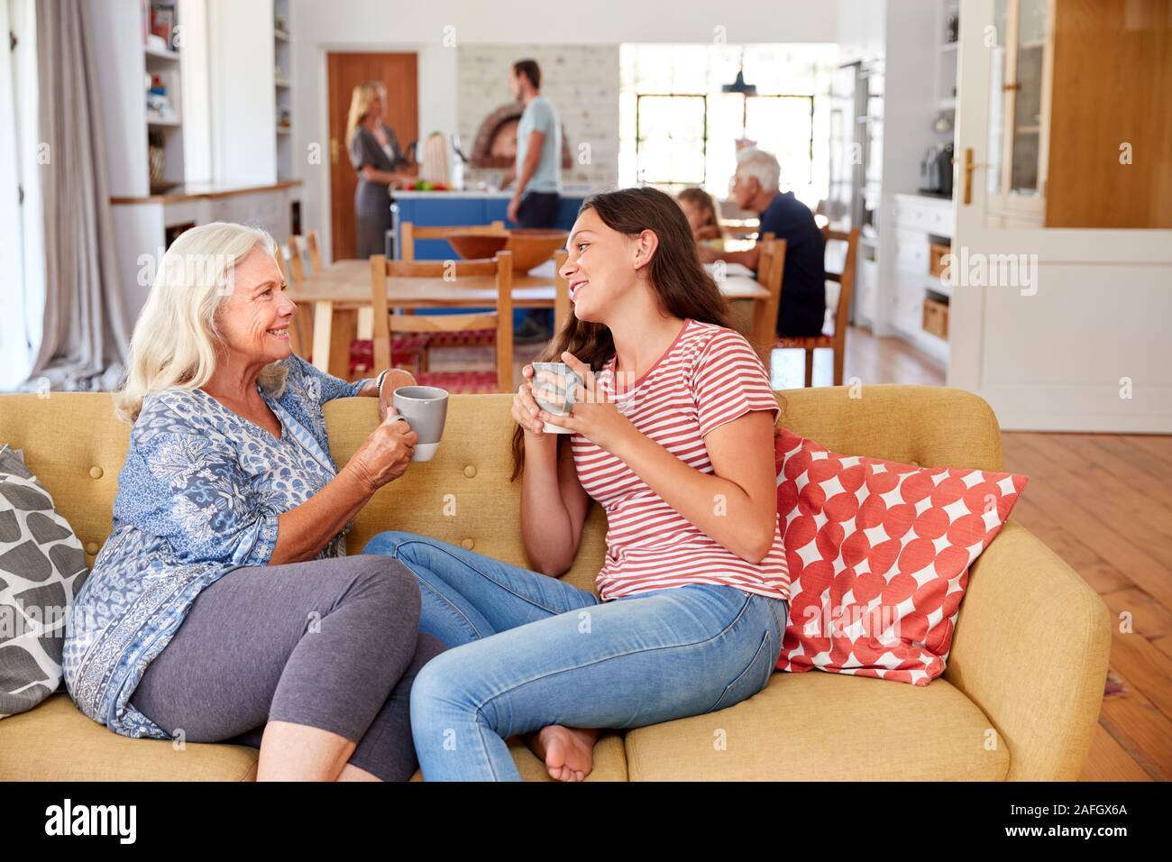 Oma mit Enkelin im Teenageralter entspannt auf einem Sofa und zu Hause sprechen Stockfoto