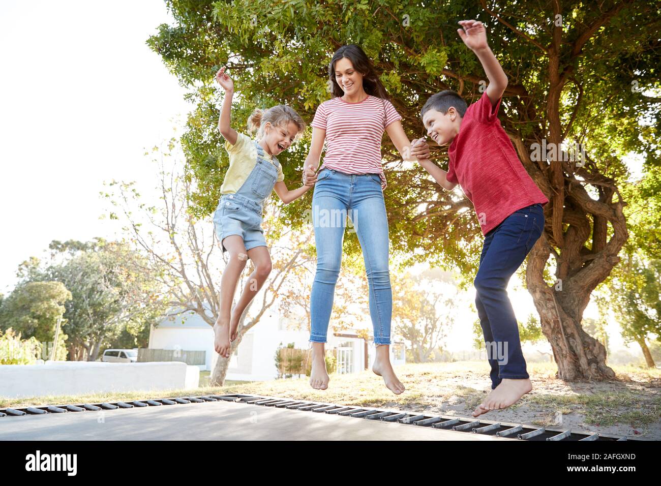 Geschwister mit Jugendlichen Schwester Spielen auf Outdoor Trampolin im Garten Stockfoto