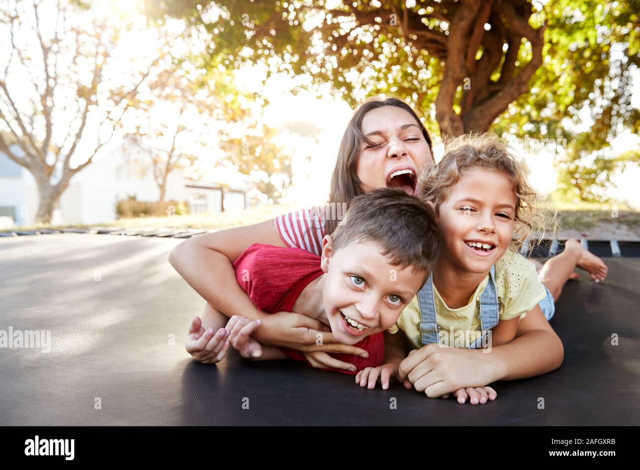 Portrait von Geschwistern mit Jugendlichen Schwester Spielen auf Outdoor Trampolin im Garten Stockfoto