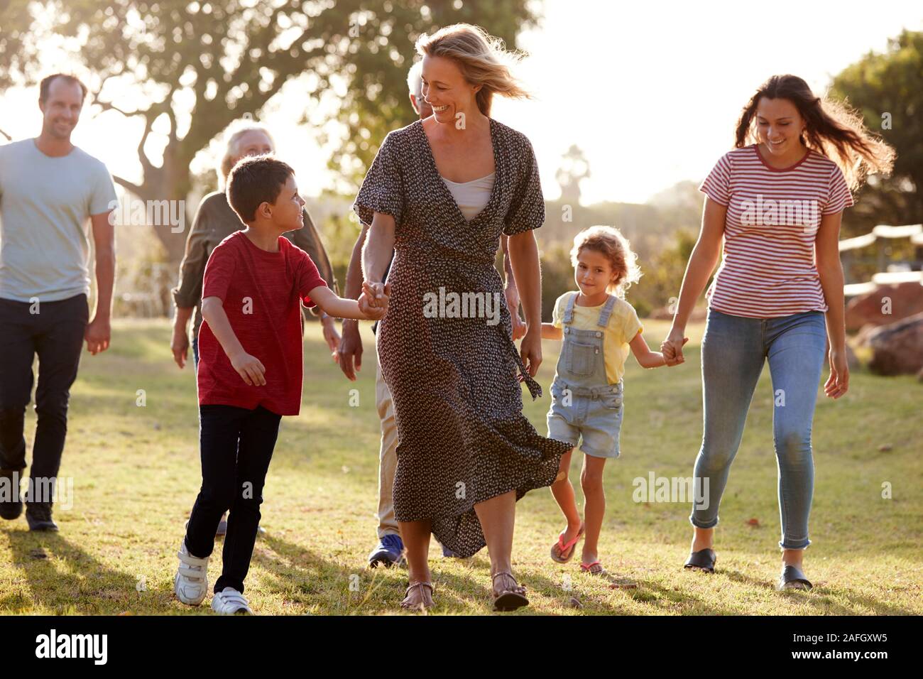 Multi-Generation Familie wandern in die Landschaft gegen das Abfackeln von Sun Stockfoto