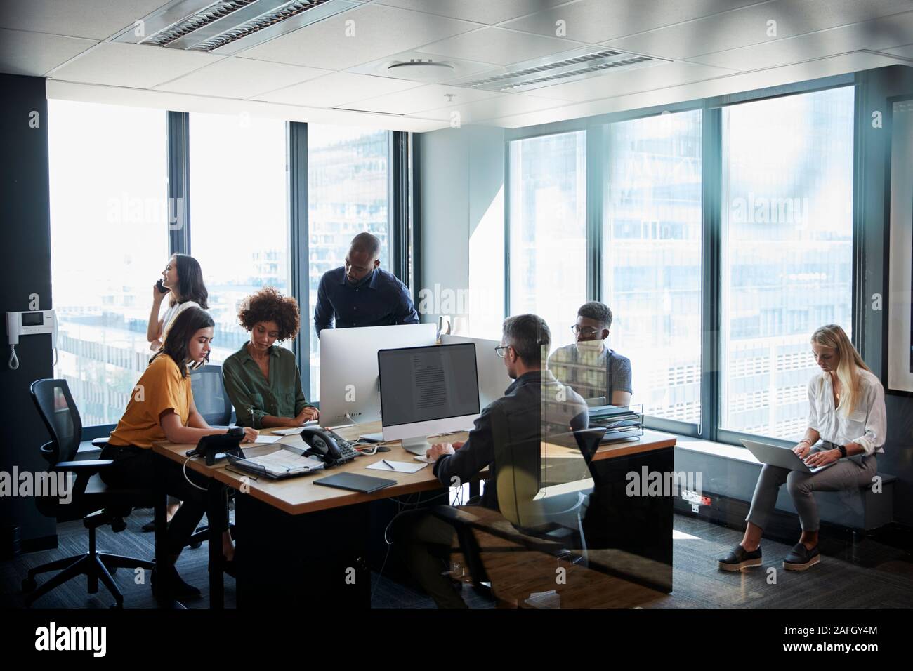 Creative Business Team gemeinsam in einer geschäftigen casual Büro, durch die Glastür gesehen Stockfoto