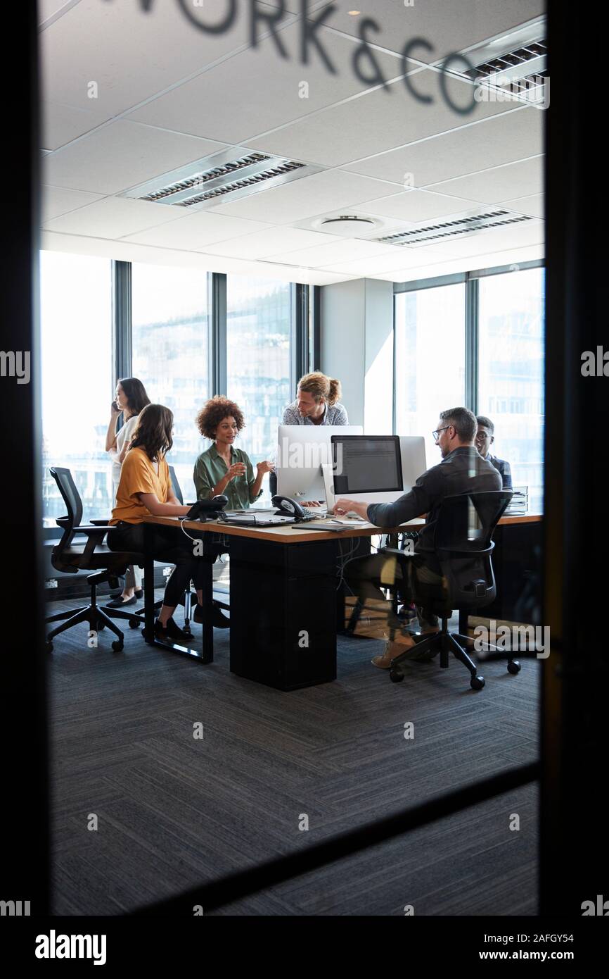 Creative Business Team arbeitet in einem gemütlichen Büro, durch Glaswand mit Text darauf gesehen, vertikal Stockfoto