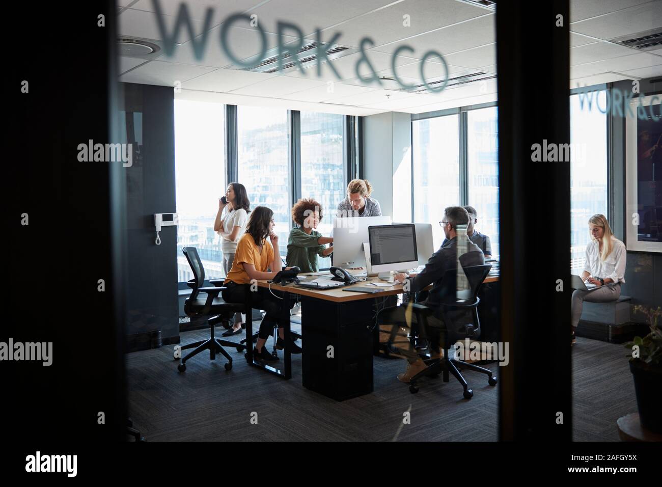 Creative Business Team arbeitet in einem gemütlichen Büro, durch Glaswand mit Text gesehen auf es Stockfoto