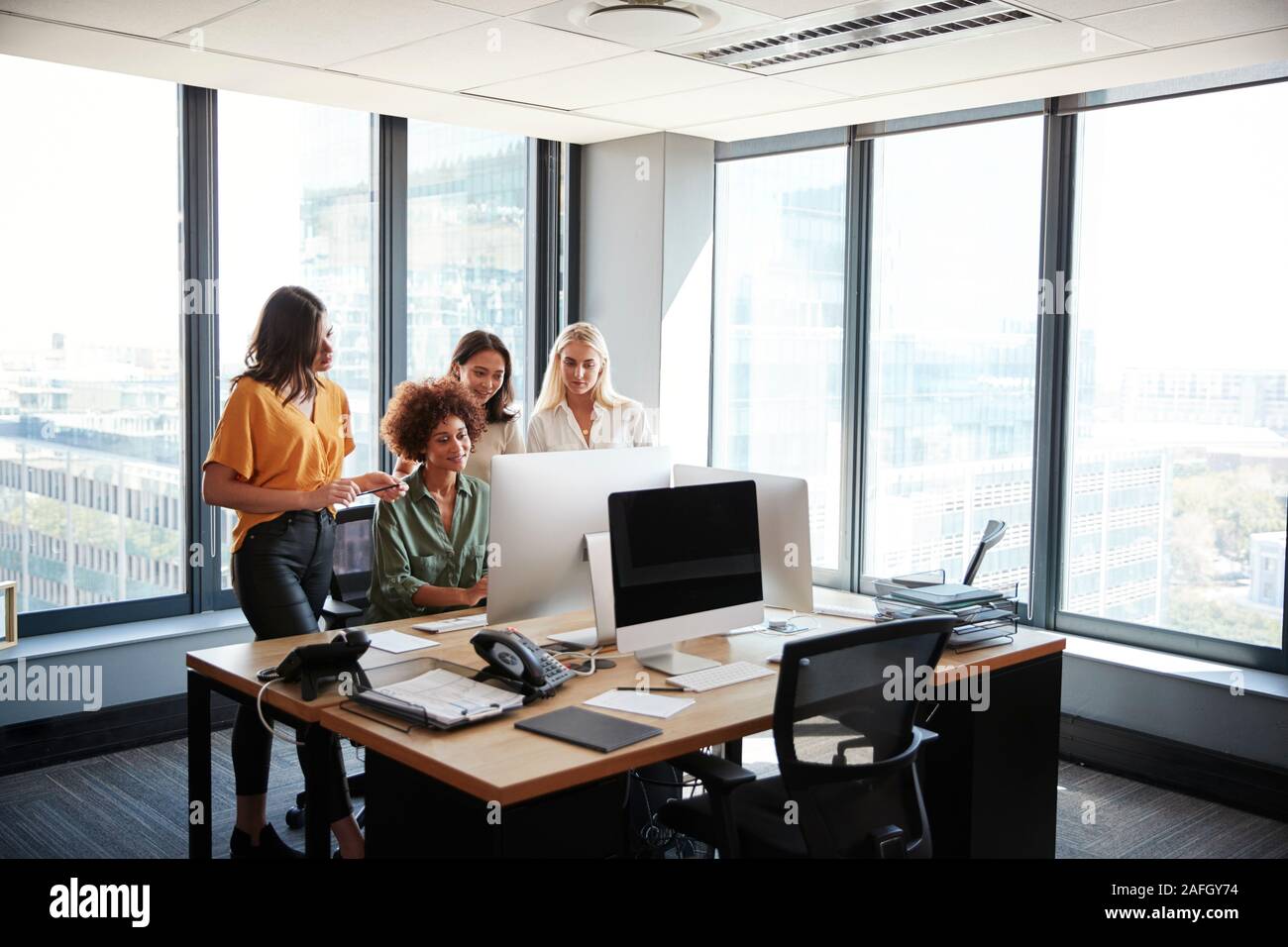 Vier weibliche creatives Arbeiten am PC-Monitor in einem Büro, in voller Länge ansehen Stockfoto