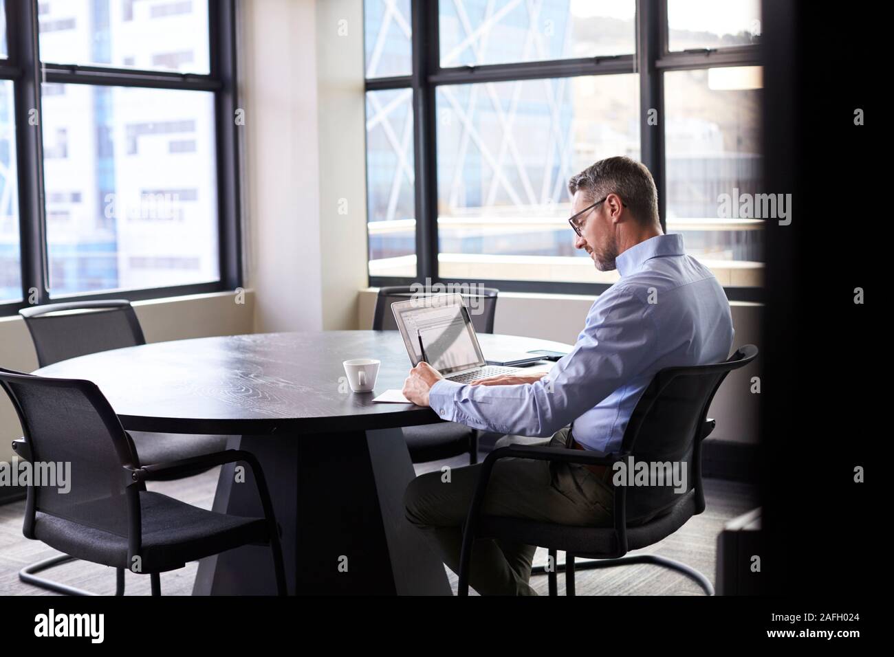 Im mittleren Alter weiße Unternehmer allein in einem Raum arbeiten, vom Eingang gesehen Stockfoto