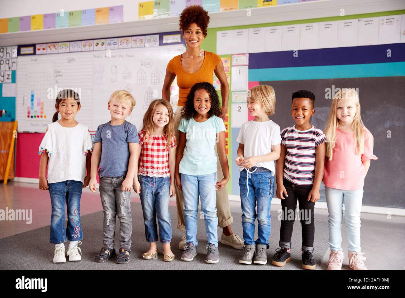 Portrait von Grundschülern im Klassenzimmer mit Lehrerin stehend Stockfoto