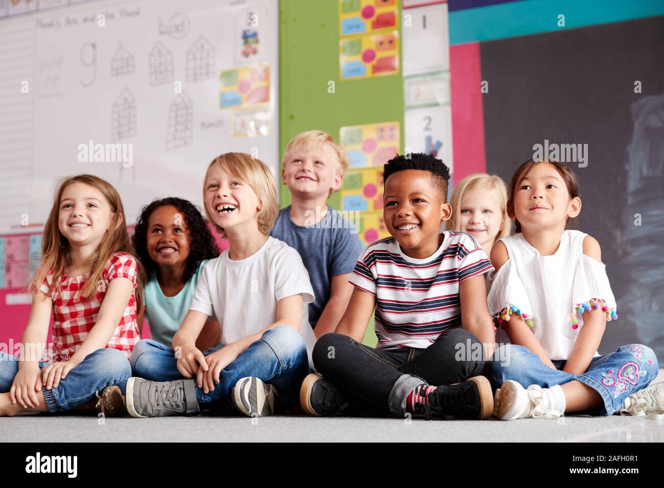 Gruppe von Grundschülern sitzen auf dem Boden im Klassenzimmer Stockfoto