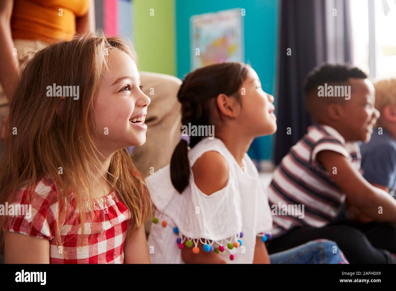 Gruppe von Grundschülern sitzen auf dem Boden hören Lehrer Stockfoto