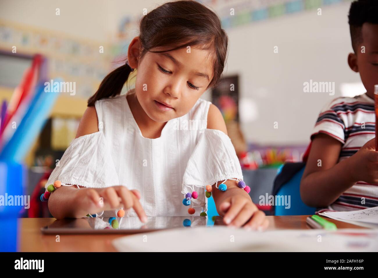 Weiblichen Schüler in der Volksschule Zeichnung mit digitalen Tablette im Klassenzimmer Stockfoto