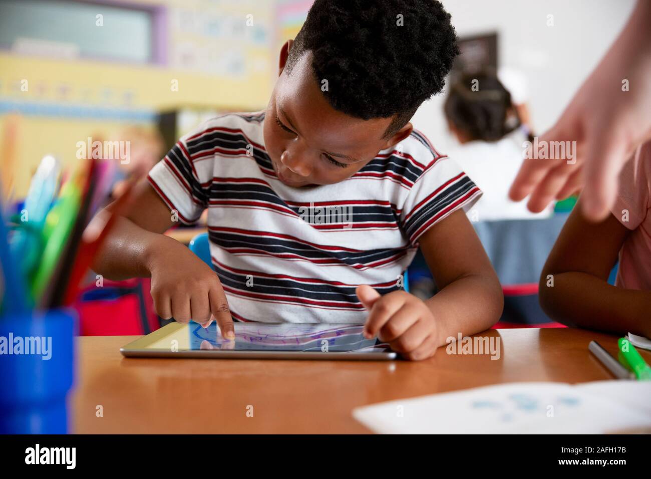 Männliche Schüler in der Volksschule Zeichnung mit digitalen Tablette im Klassenzimmer Stockfoto