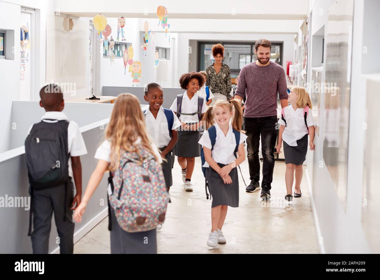 Lehrer und Schüler Entlang Korridor In besetzt Grundschule Korridor Stockfoto