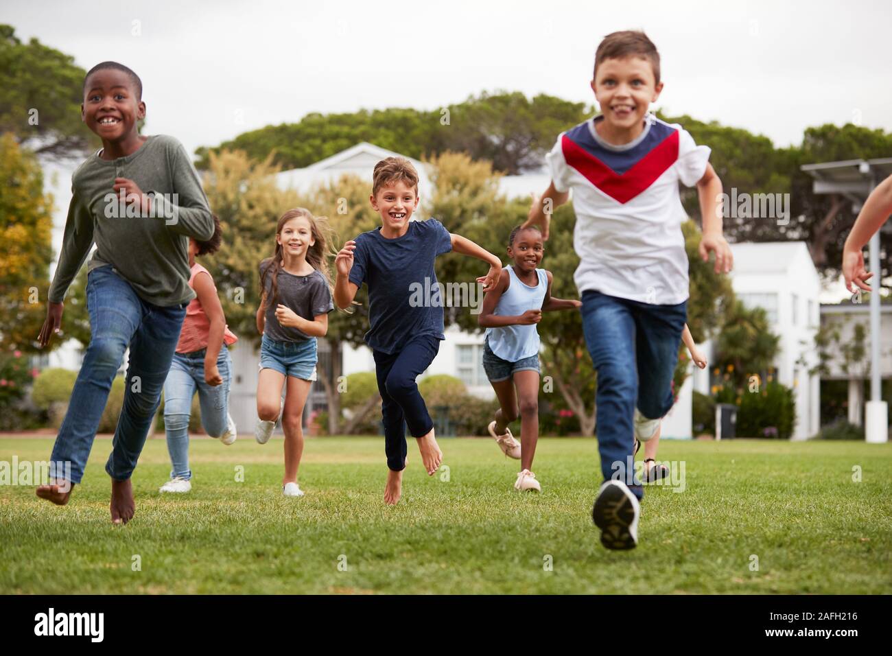 Aufgeregt Grundschülern über Feld in den Pausen laufen Stockfoto