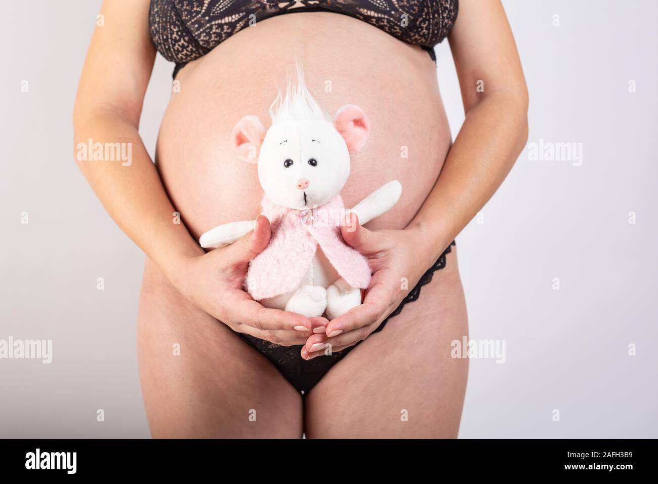 Close-up schwangere Frau Bauch mit Maus Spielzeug. Schöne schwangere Frau. Schwangerschaft, Elternschaft, Vorbereitung und Erwartung Konzept. Stockfoto