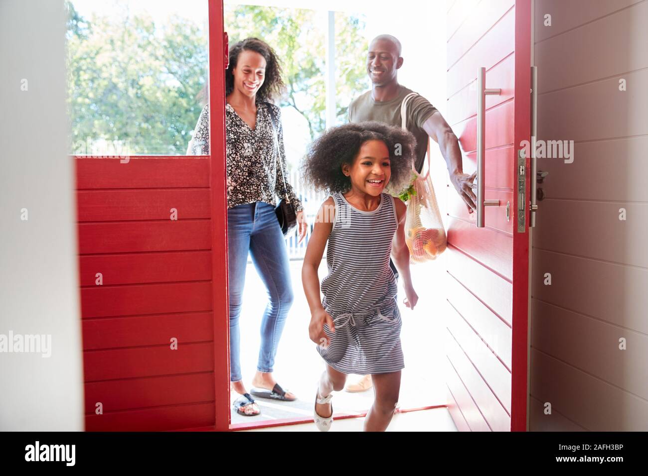 Familie Heimweg von Shopping Trip mit Kunststoff Kostenlose Einkaufstaschen Öffnen der vorderen Tür Stockfoto