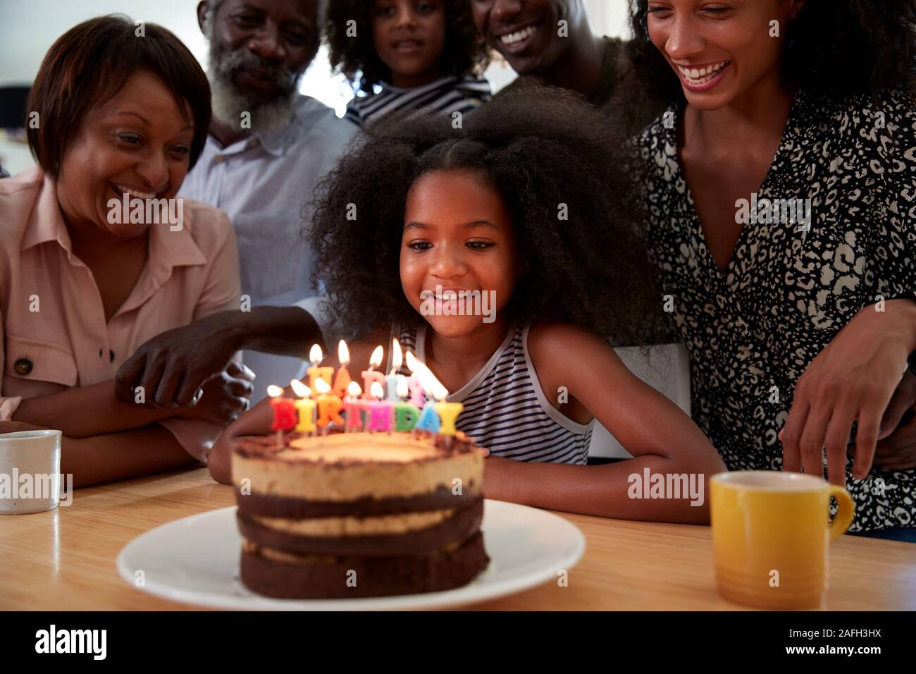 Multi-Generation Familie feiern Enkelinnen Geburtstag zu Hause mit Kuchen und Kerzen Stockfoto