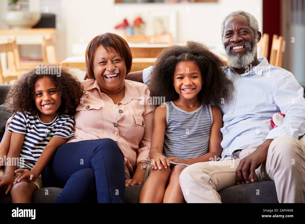 Portrait von lächelnden Großeltern mit Enkeln Sitzen auf einem Sofa zu Hause Entspannende zusammen Stockfoto